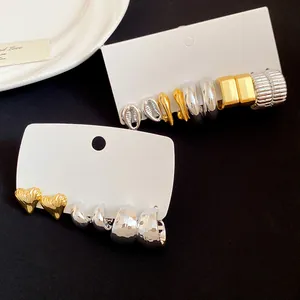 Detailed view of various vintage gold and silver earring sets displayed on white cards.
