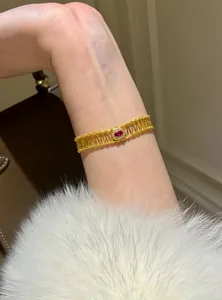 Detailed macro view of a vintage gold openwork bracelet with red zircon on arm