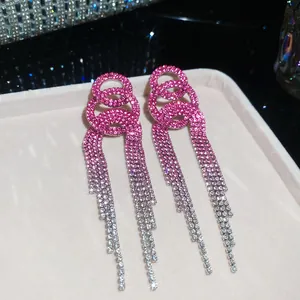 Detail view of pink and silver gradient rhinestone tassel earrings on a jewelry display tray