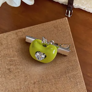 Gros plan sur la pince à cheveux pomme verte avec cœur en zircon brillant.