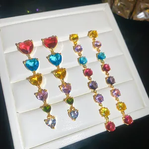 Gros plan de boucles d'oreilles plaquées or 18 carats avec zircons multicolores en cœur.