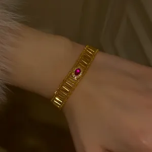 Detailed view of a vintage gold hollow bracelet with a red zircon gemstone on a wrist.