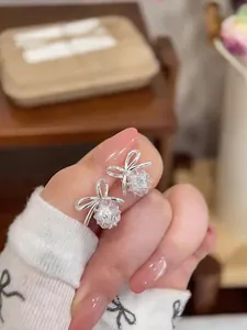 Close-up detail of elegant silver-toned bow-knot stud earrings with sparkly clear zircon stones