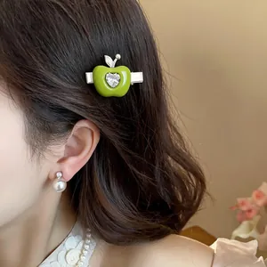Gros plan d'une pince à cheveux en forme de pomme verte avec un cœur en zircon brillant