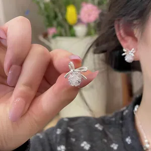 Close-up of elegant silver bow stud earrings with sparkling zircon crystal pendants.