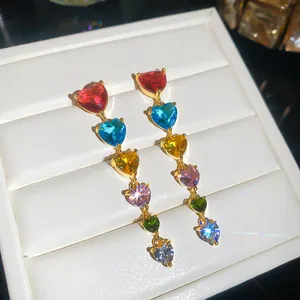 Gros plan exquis de zircons multicolores en forme de cœur sur boucles d'oreilles dorées