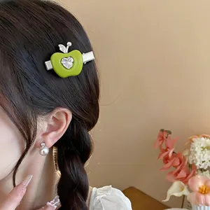 Détail d'une pince à cheveux pomme verte en résine avec un cœur en zircon brillant