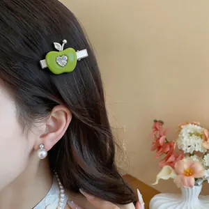 Gros plan détaillé montrant une pince à cheveux pomme verte en résine avec zircon
