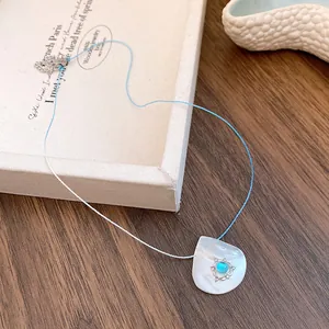 Detailed view of shell pendant necklace with blue gemstone and bicolored cord