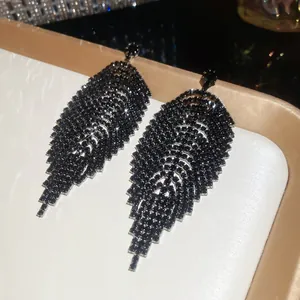 Detailed view of elegant black rhinestone leaf tassel earrings featuring silver needles.