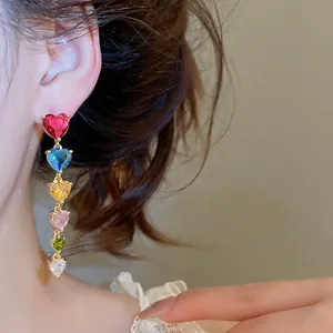 Gros plan détaillé de boucles d'oreilles pendantes en forme de cœur en zircon arc-en-ciel