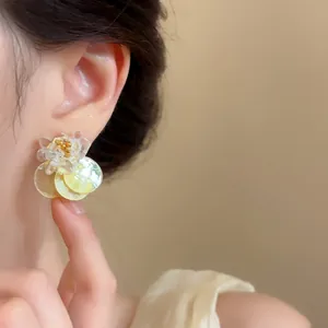 Detailed view of shell flower stud earrings with transparent petals on an ear.