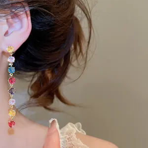 Détail de boucles d'oreilles pendantes en CZ multicolores portées par un mannequin.