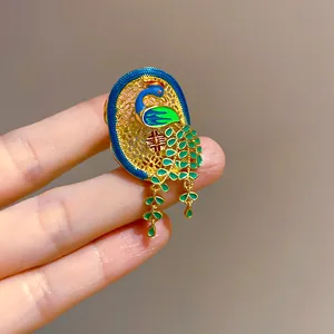 Detail view of 18K gold-plated peacock open ring with green enamel and dangle charms