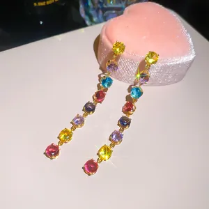 Gros plan de boucles d'oreilles longues avec zircons multicolores et placage à l'or.