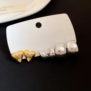 Close-up of vintage heart and geometric silver stud earring set on white card.