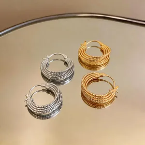 Vista dettagliata di orecchini a cerchio intrecciati placcati oro 18k oro e argento