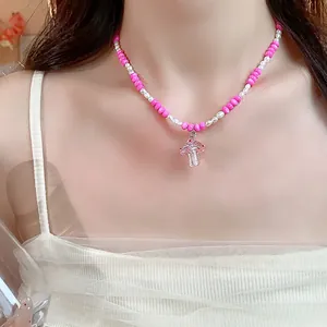 Vue détaillée d'un collier de perles roses et blanches avec un pendentif en champignon.