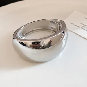 Close-up view of a minimalist silver wide metal cuff bracelet with secure hinged clasp