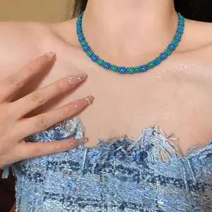 Squisito primo piano di una collana girocollo vintage in perle di vetro blu e verdi su una modella