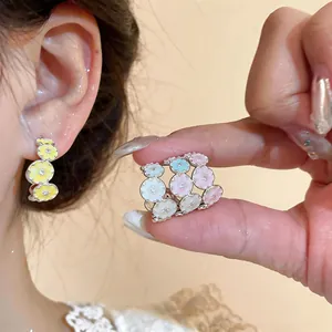 Detailed macro shot of colorful enamel flower C-shaped earrings with zircon studs