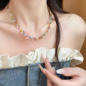Détail d'un collier de perles transparentes avec des accents colorés sur le décolleté