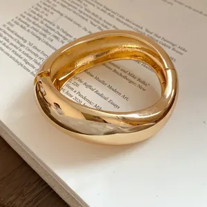 Close-up detail of a chunky gold metal bracelet with a stylish textured wrinkle design.