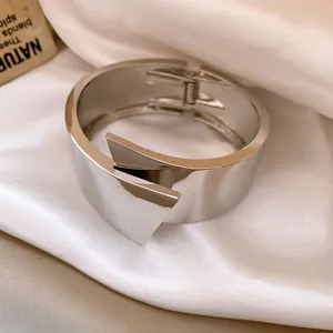 Close-up detail of a silver wide metal cuff bracelet featuring geometric layered design