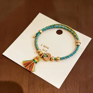Nahaufnahme eines bunten gewebten Armbands mit Quaste und Glücksbringer-Detail