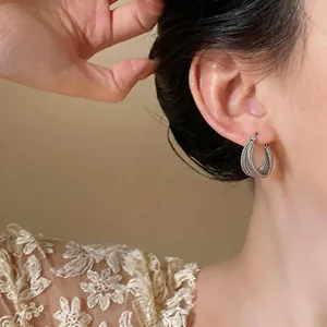 Primo piano di un elegante orecchino a cerchio intrecciato color argento su una modella