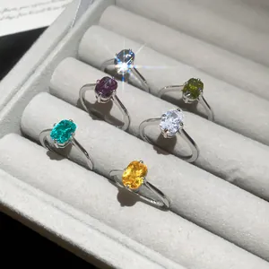 Detailed view of six minimalist silver rings with colorful square-cut gemstones in a tray.