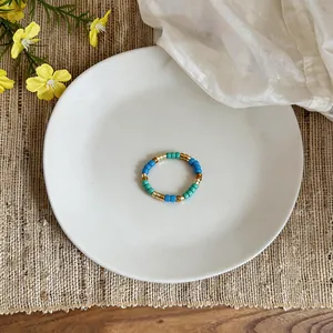 Primo piano di un anello vintage con perline di vetro blu e oro su un piatto bianco