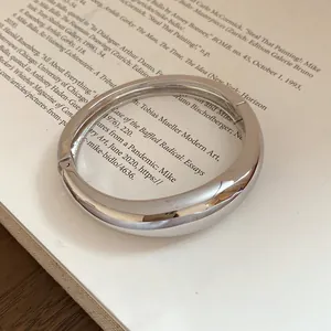 Detailed view of a silver chunky metal hinged bangle with a high-polished mirror finish