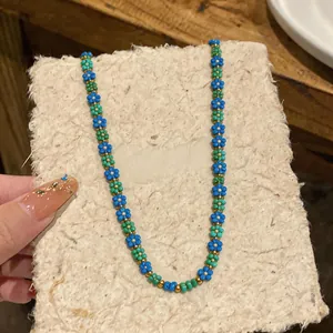Primo piano di una collana retrò in perle di vetro con motivi floreali blu e verdi.