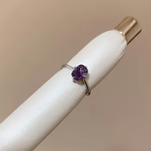 Close-up detail of a minimalist silver open ring featuring a purple cushion-cut stone