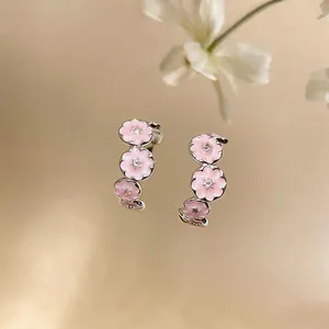 Macro detail view of C-shaped earrings with pink enamel flowers and zircon centers