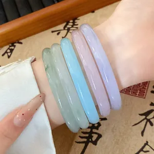 Close-up detail showing five colorful translucent glass bracelets worn on a wrist in Hanfu