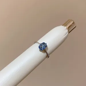 Close-up detail of a minimalist silver ring featuring a cushion-cut blue gemstone