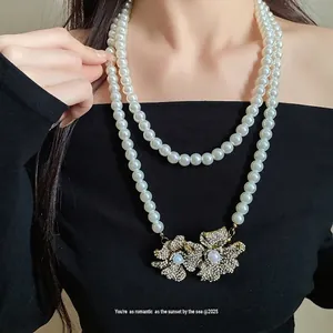 Elegant double-layered vintage pearl necklace featuring a sparkling rhinestone flower pendant