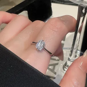 Close-up of minimalist silver-toned ring with oval cut clear stone on finger
