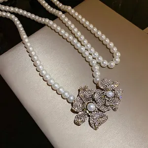 Vintage style pearl strand necklace with dual rhinestone-encrusted flower pendants.