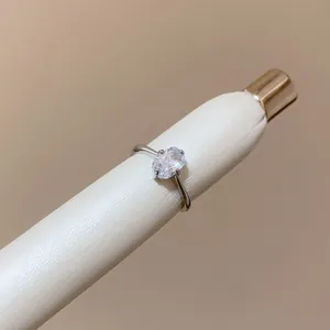 Close-up detail of a minimalist silver ring featuring a clear oval-cut gemstone.