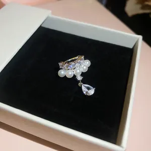Detailed view of a zircon and pearl ear cuff with a teardrop dangle in a jewelry box
