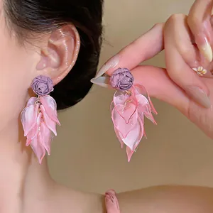 Detail view of the pink acrylic petal tassel earrings with purple fabric flower studs.