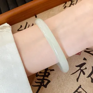 Macro view of a pale green translucent glass bangle on a wrist in Hanfu style