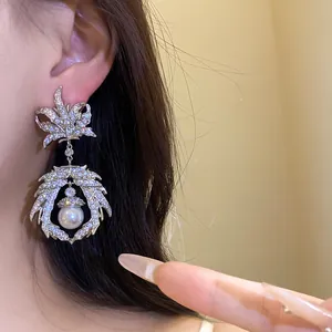 Macro detail of vintage silver-tone maple leaf earrings with zircon and pearl drop.