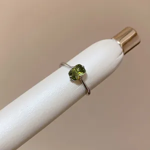 Macro view of a silver ring with a rectangular green gemstone set in a four-prong mount.