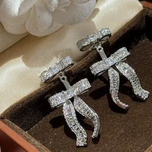 Detailed macro view of elegant 18k gold plated silver needle bow earrings with sparkling zircons