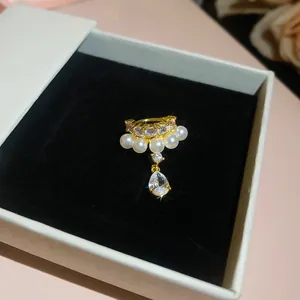 Detail view of an elegant gold ear cuff with white pearls and a pear-shaped zircon drop