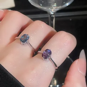 Close-up of two elegant rings with oval color-changing gemstones worn on fingers.